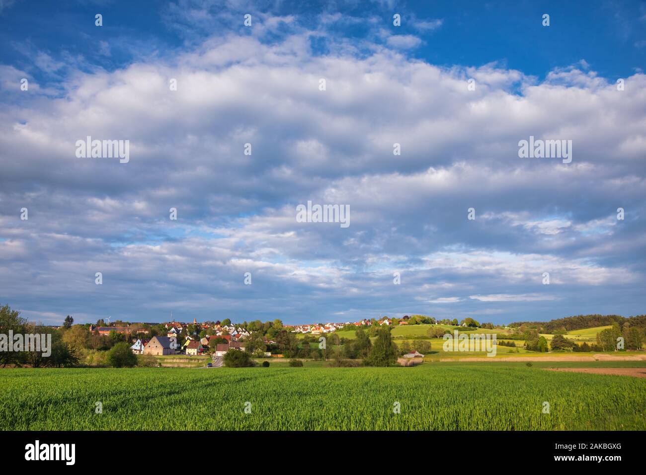 Bavarian spring rural landscape with green field and town in background ...