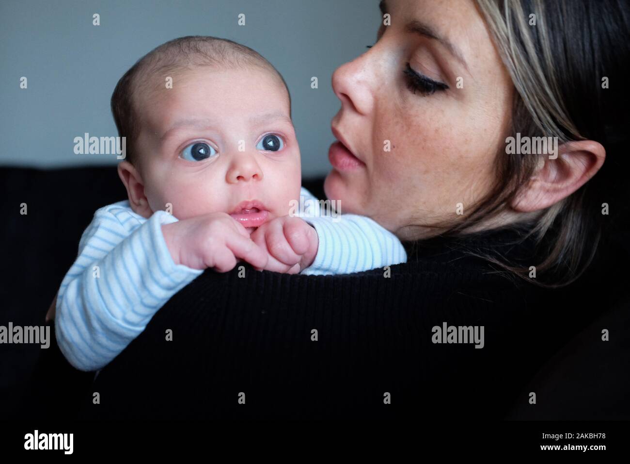 Young mother with her new baby son of 1 month old with big eyes Stock Photo