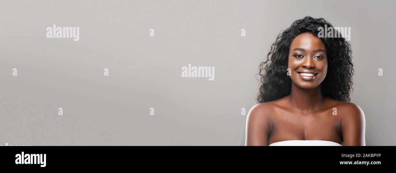 Beauty portrait of attractive black woman with perfect smooth skin and white smile over gray background, extreme long shot, wide banner, panorama Stock Photo