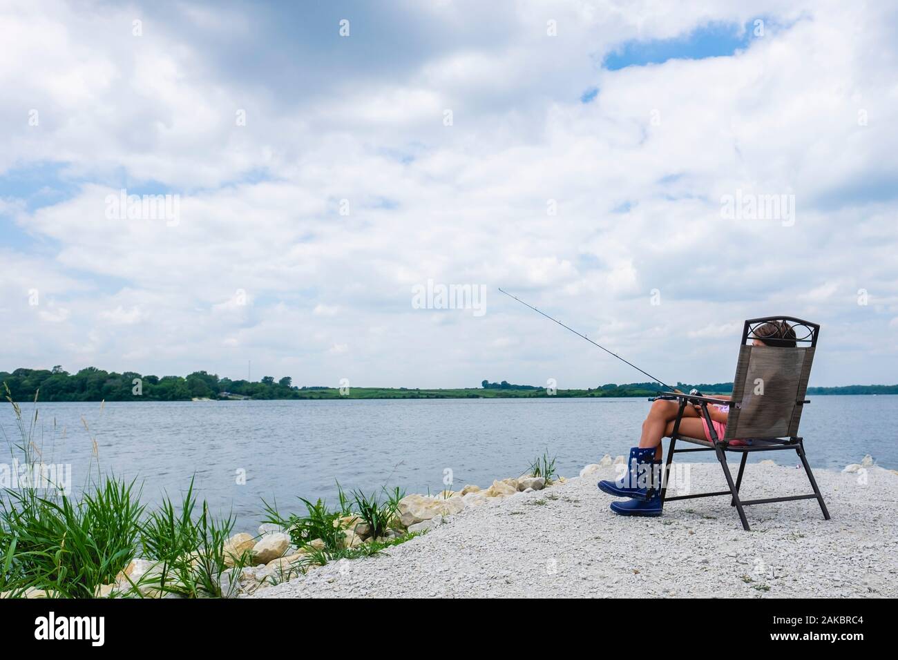Tween girl 10-12 years old sitting outdoors by water fishing Stock Photo