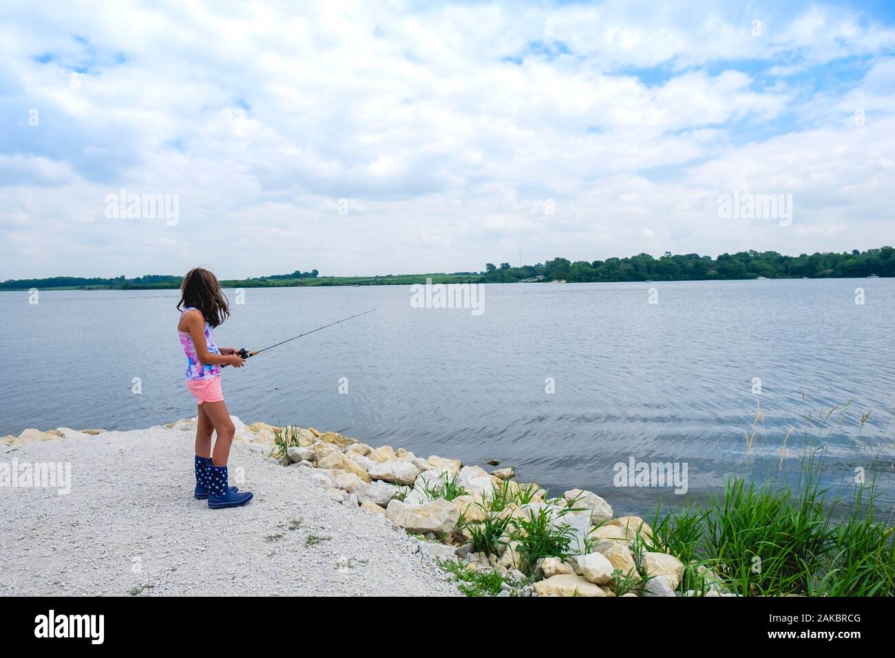 Teen Girl 10-12 years old standing near water fishing on summer day Stock Photo
