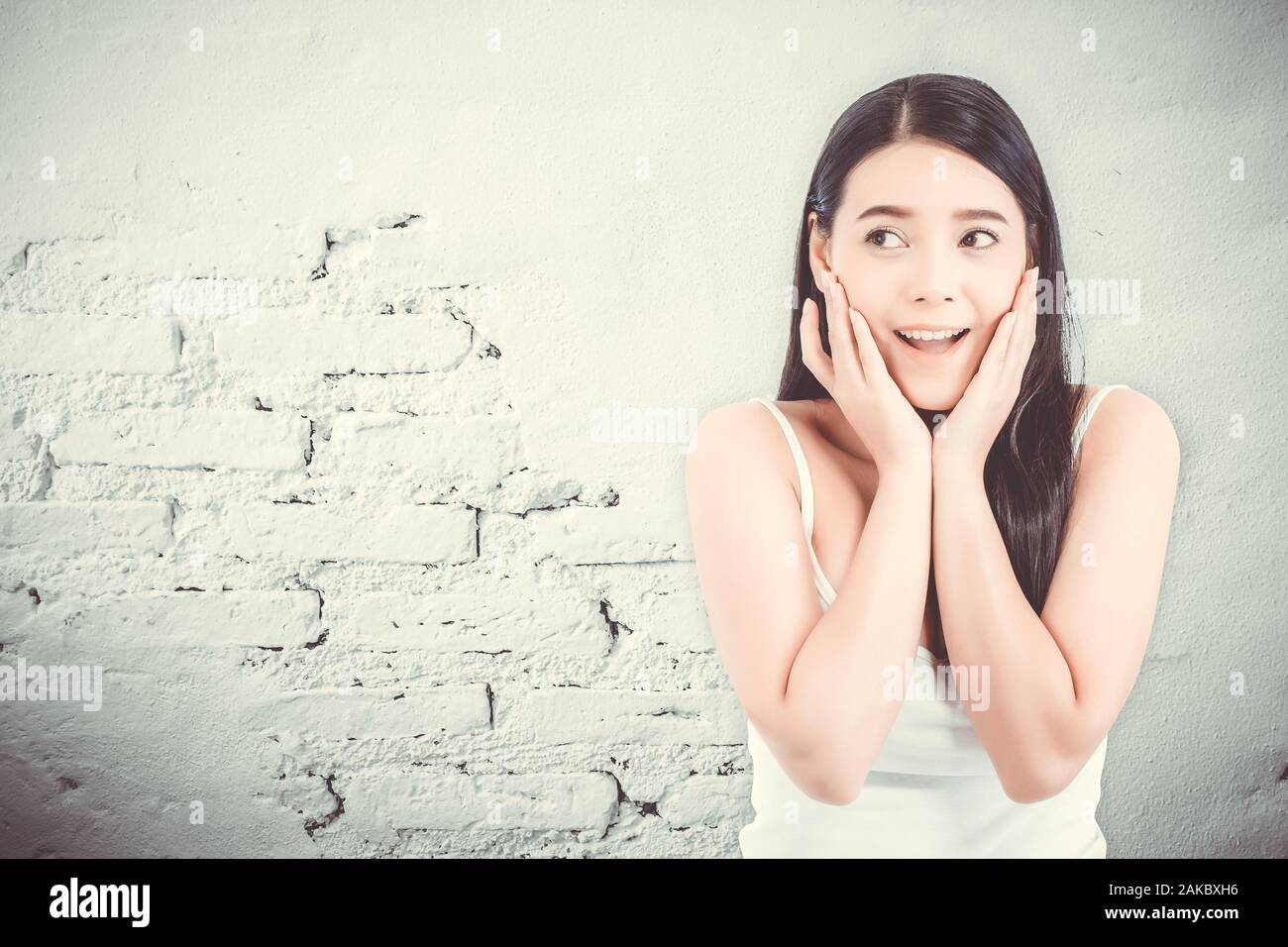 Asian woman surprise hold cheek with hand, Beautiful girl with presenting your product with expression excited and surprise on cement background, Expr Stock Photo