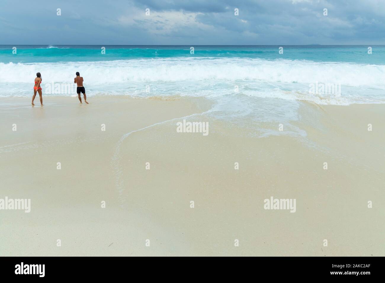 Seychelles, La Digue Island, swimmers in the waves on the beach of the cove Stock Photo