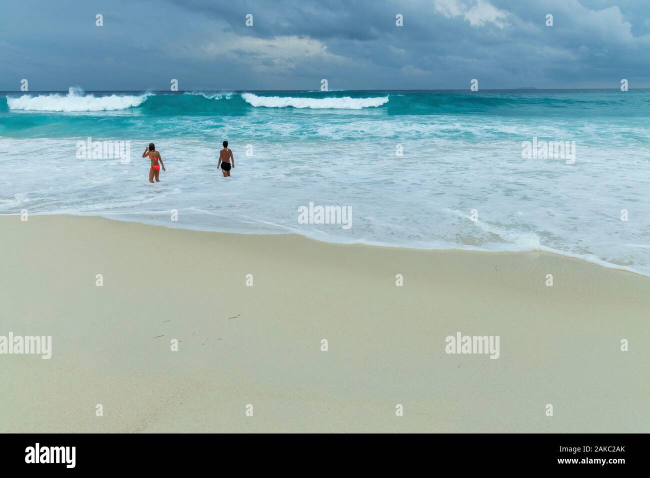 Seychelles, La Digue Island, swimmers in the waves on the beach of the cove Stock Photo