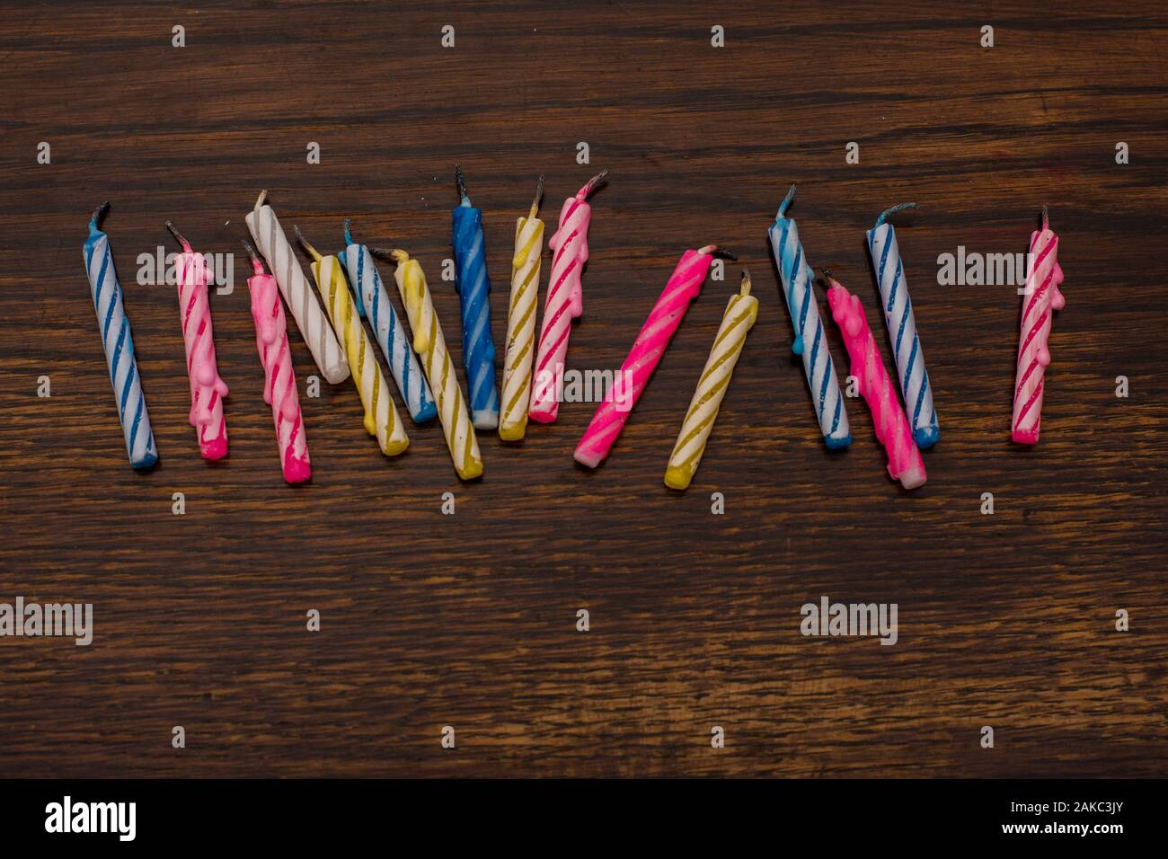 Close-up of colorful birthday cake candles on the background of an old wooden table Stock Photo