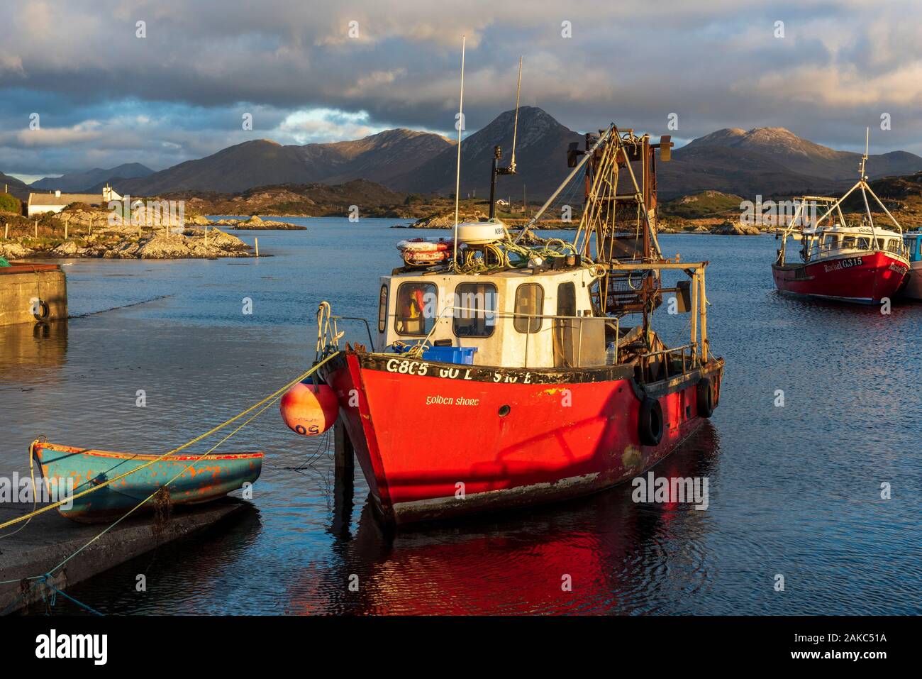 Ireland, County Galway, Connemara, Ballynakill, wooden boats and fishing boats in the harbour, Tully Mountains and Twelve Bens mountains in the background Stock Photo
