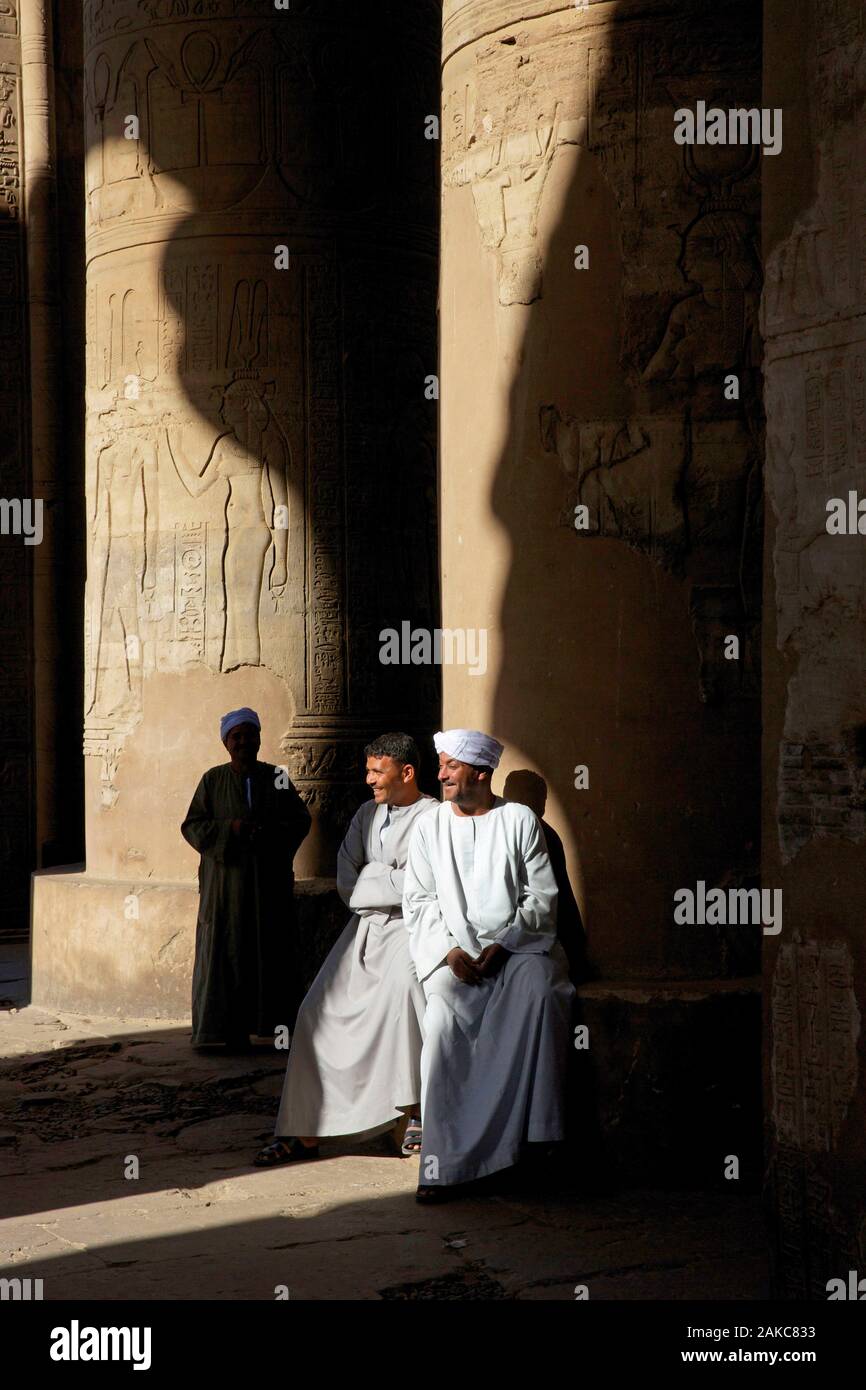 Egypt, Upper Egypt, Nile Valley, Kom Ombo, Turbaned temple guards look amused at the foot of a column of Kom Ombo temple between shadow and light Stock Photo