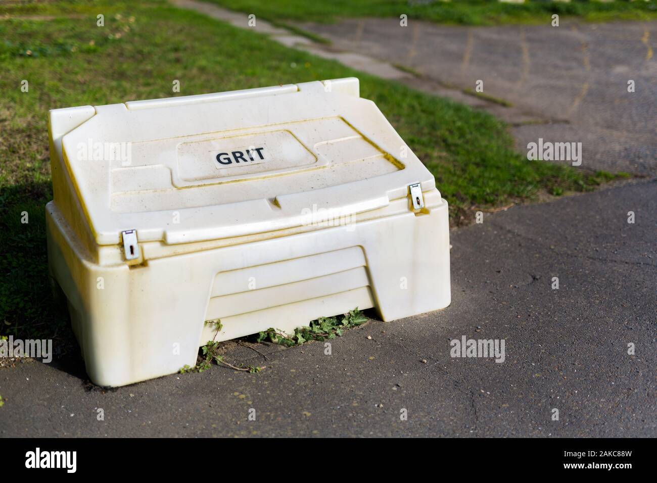 A yellow grit box located in the ground of a rural village hall for use