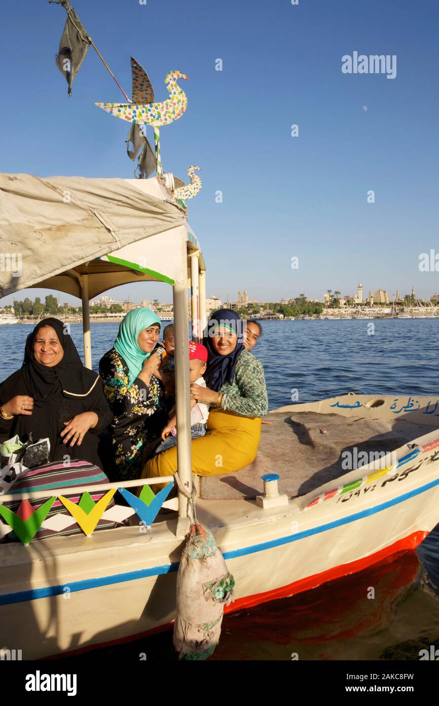 Egypt, Upper Egypt, Nile Valley, Luxor, Egyptian women smiling on a river shuttle crossing the Nile in front of the city of Luxor Stock Photo