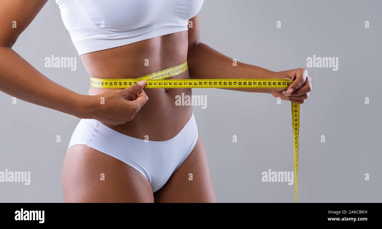 https://c8.alamy.com/comp/2AKCBKH/close-up-of-young-african-woman-measuring-her-waist-over-grey-background-well-fit-body-concept-panorama-2AKCBKH.jpg