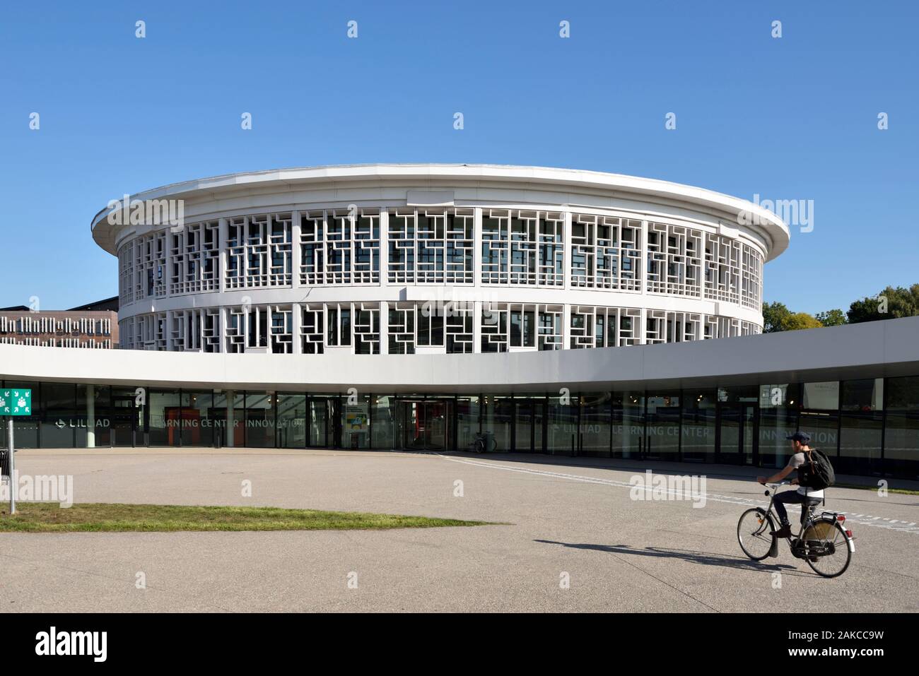 France, Nord, Villeneuve d'Ascq, University of Lille, Cité Scientifique campus, circular building housing the library and called LILLIAD (Learning Center Innovation1), a scientific center of the University of Lille (scientific university library, multimedia, large scientific collection, expanded library and digitized resources), cycling student Stock Photo