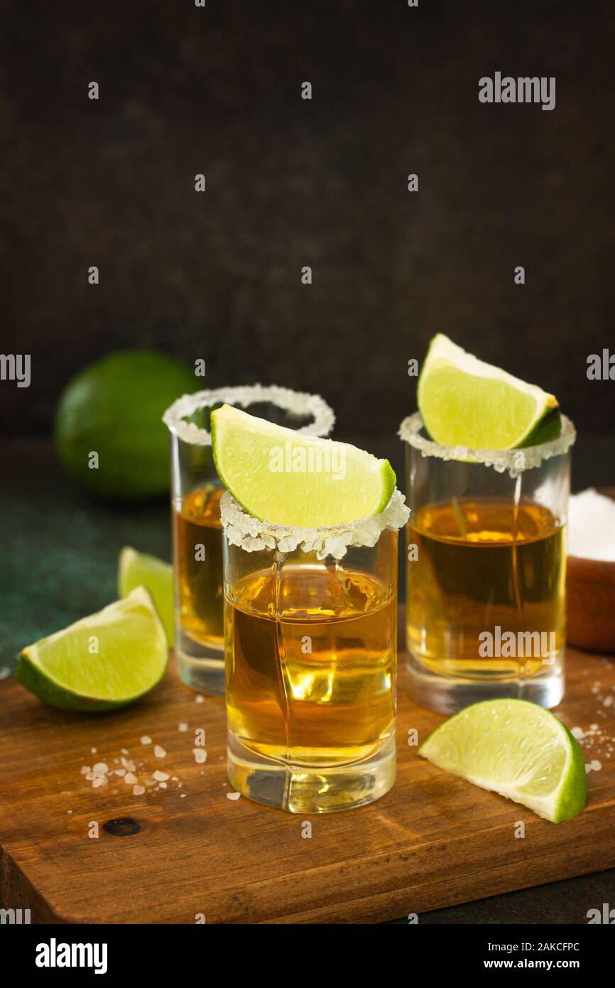 Mexican Gold Tequila shot with lime and salt on dark stone background ...