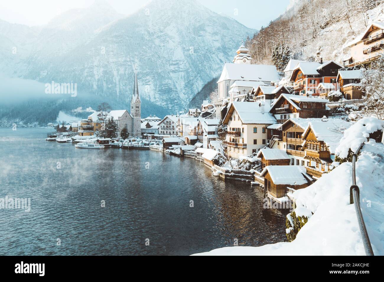 Classic postcard view of famous Hallstatt lakeside town in the Alps with passenger ship on a beautiful cold sunny day with blue sky and clouds in wint Stock Photo