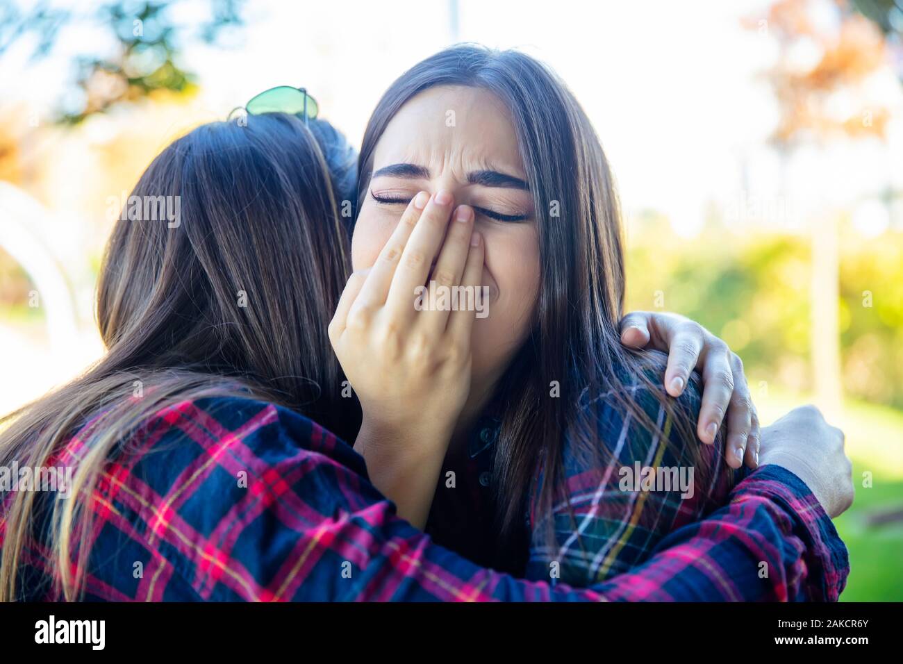 View at two sad best female friends embracing each other Stock Photo