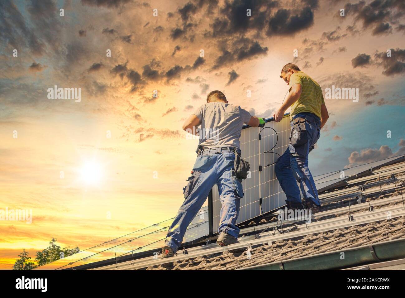 Installing solar photovoltaic panel system. Solar panel technician installing solar panels on roof. Alternative energy ecological concept. Stock Photo