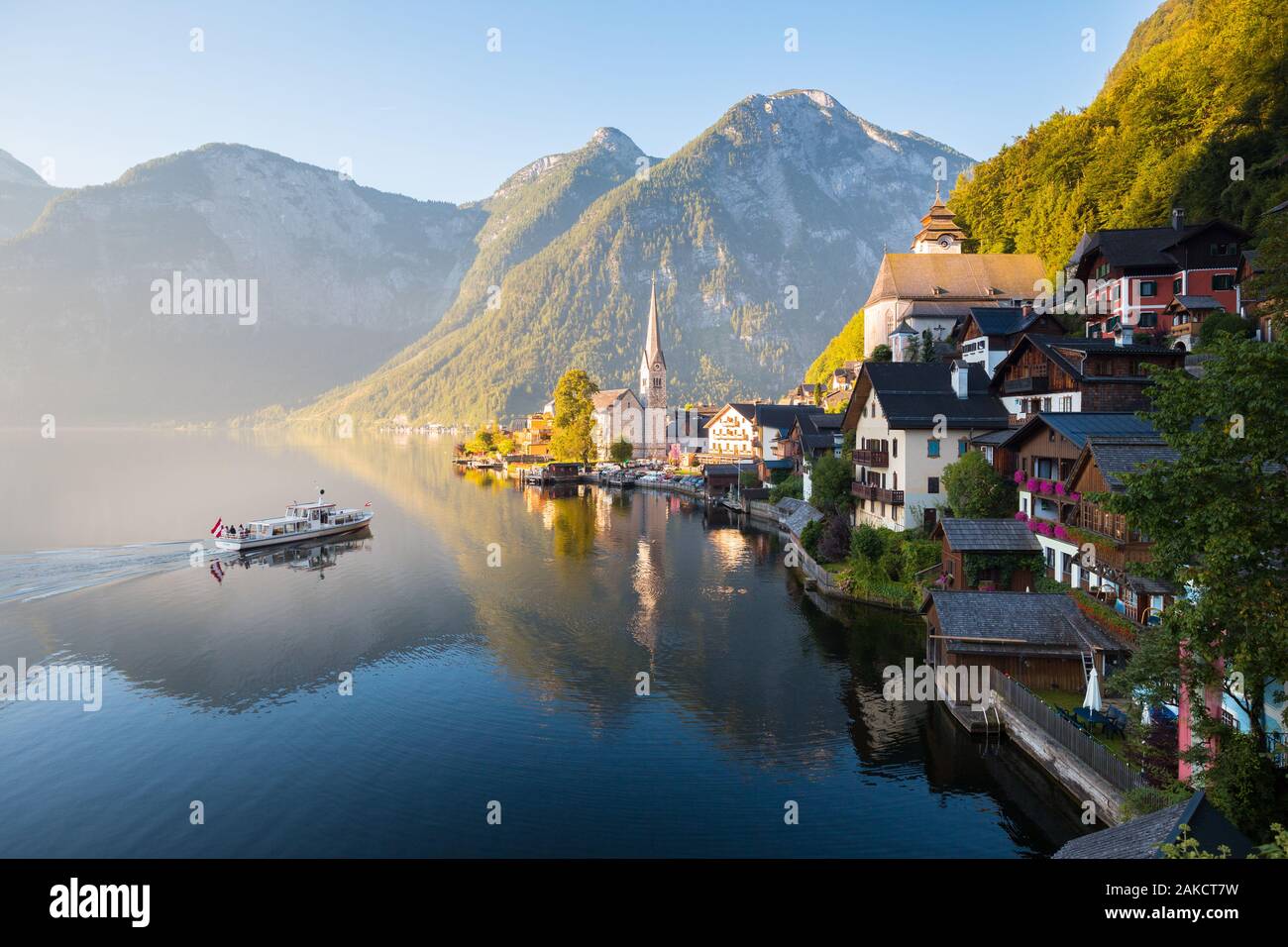 Classic postcard view of famous Hallstatt lakeside town in the Alps with traditional passenger ship in early morning light at sunrise on a beautiful d Stock Photo