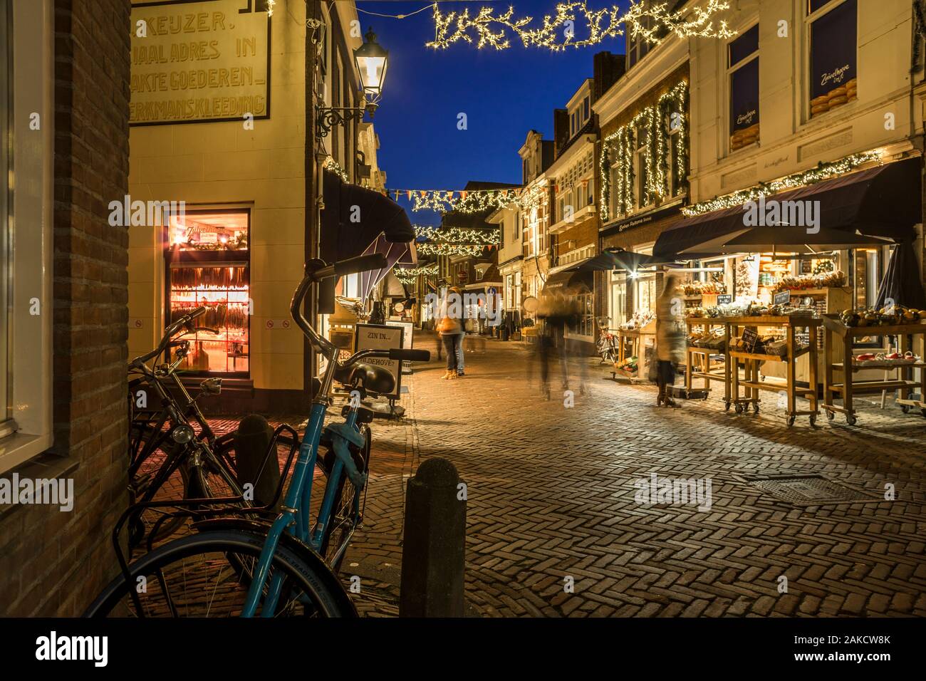 People are shopping in the 'Kleine Kerkstraat' at dusk. The street is illuminated by Christmas lights. The 'Kleine Kerkstraat' in Leeuwarden is repeat Stock Photo