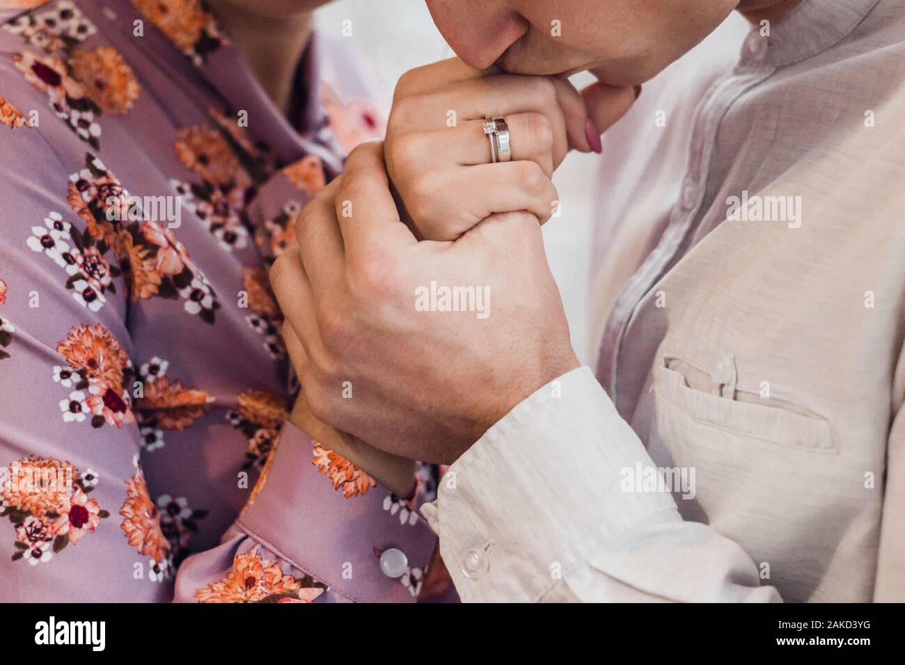 A romantic couple holding hands and kissing with wedding rings ...