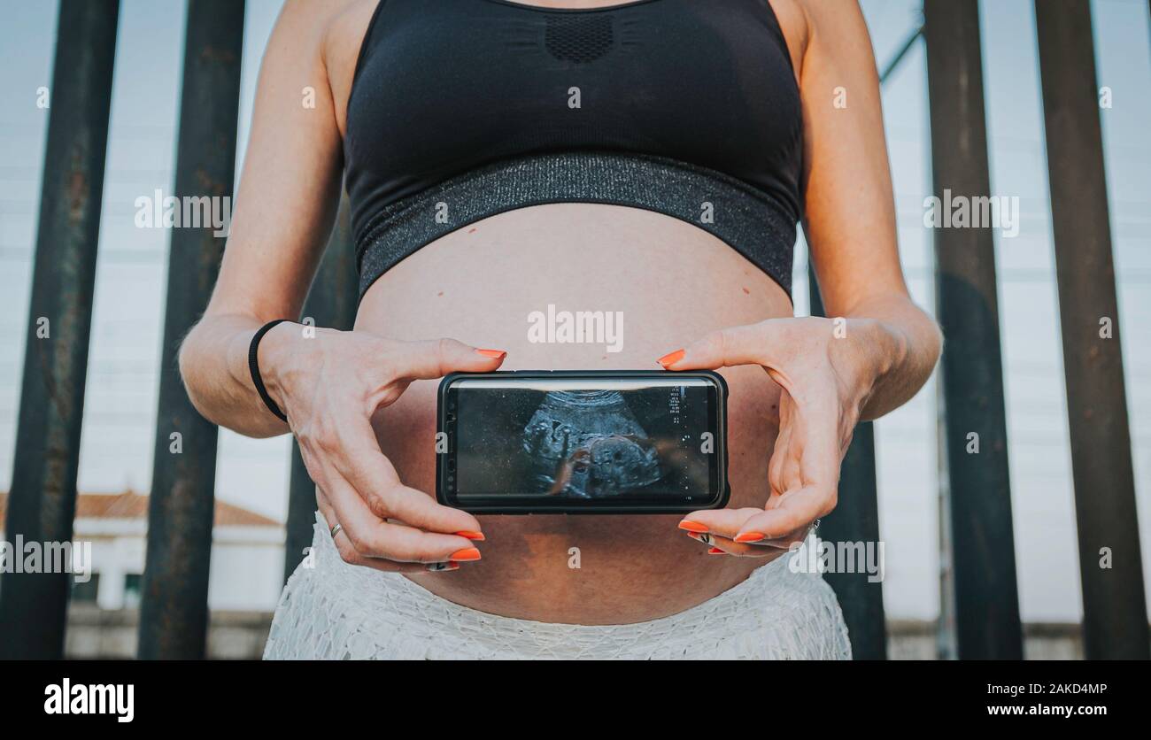 Pregnant woman holding and showing mobile phone with fetal ultrasound photo  Stock Photo - Alamy