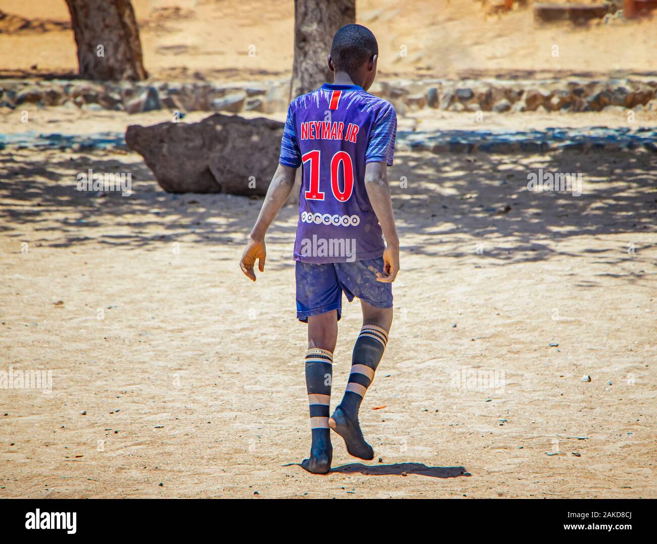 Goree island, Senegal- April 22 2019: Unidentified boy play soccer on the beach in the town in Africa. The boy is wearing a football jersey. Stock Photo