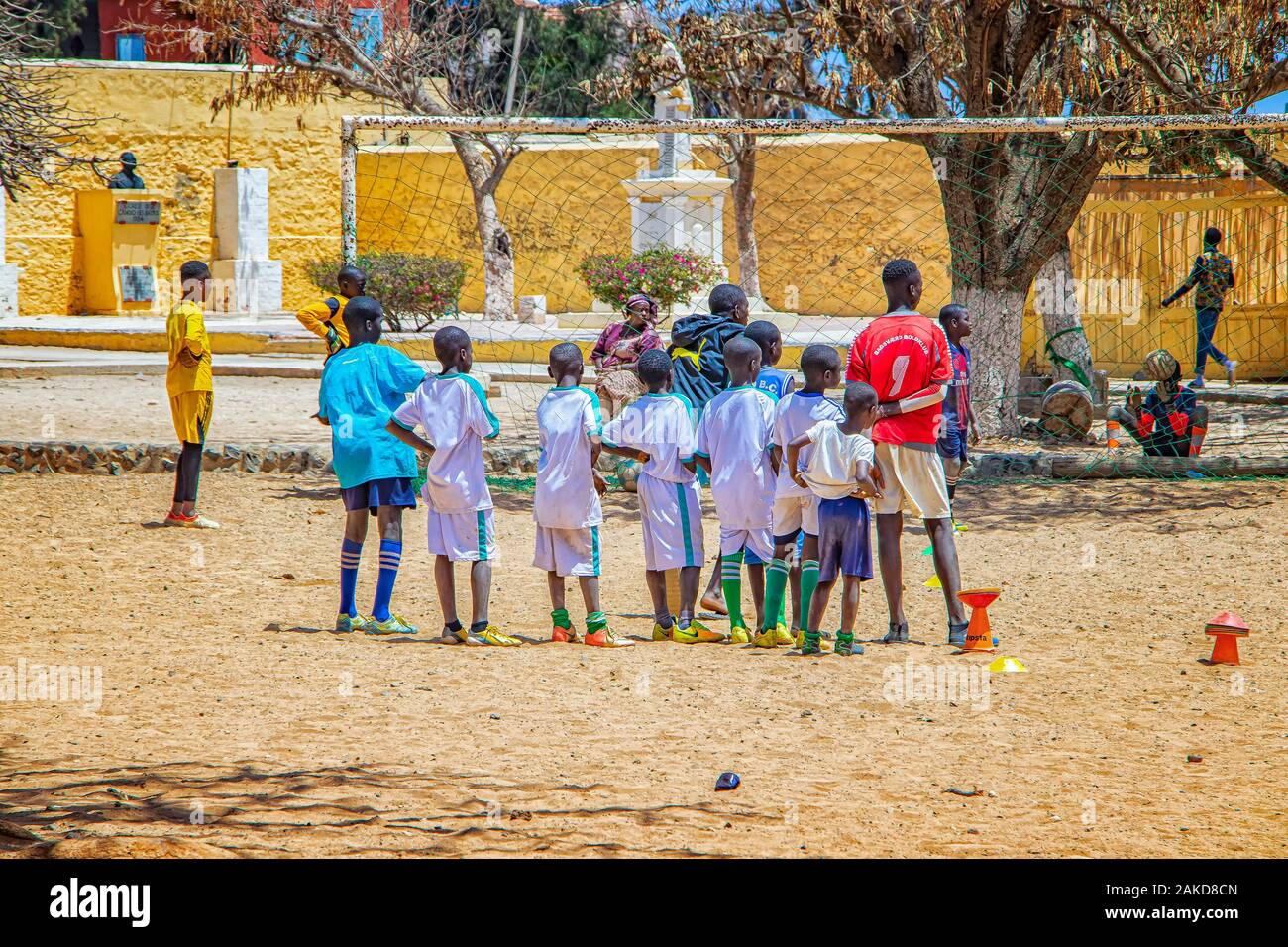Goree island, Senegal- April 22 2019: Unidentified boys play soccer on the sand in the town in Africa. The boys are wearing a white football jersey. Stock Photo
