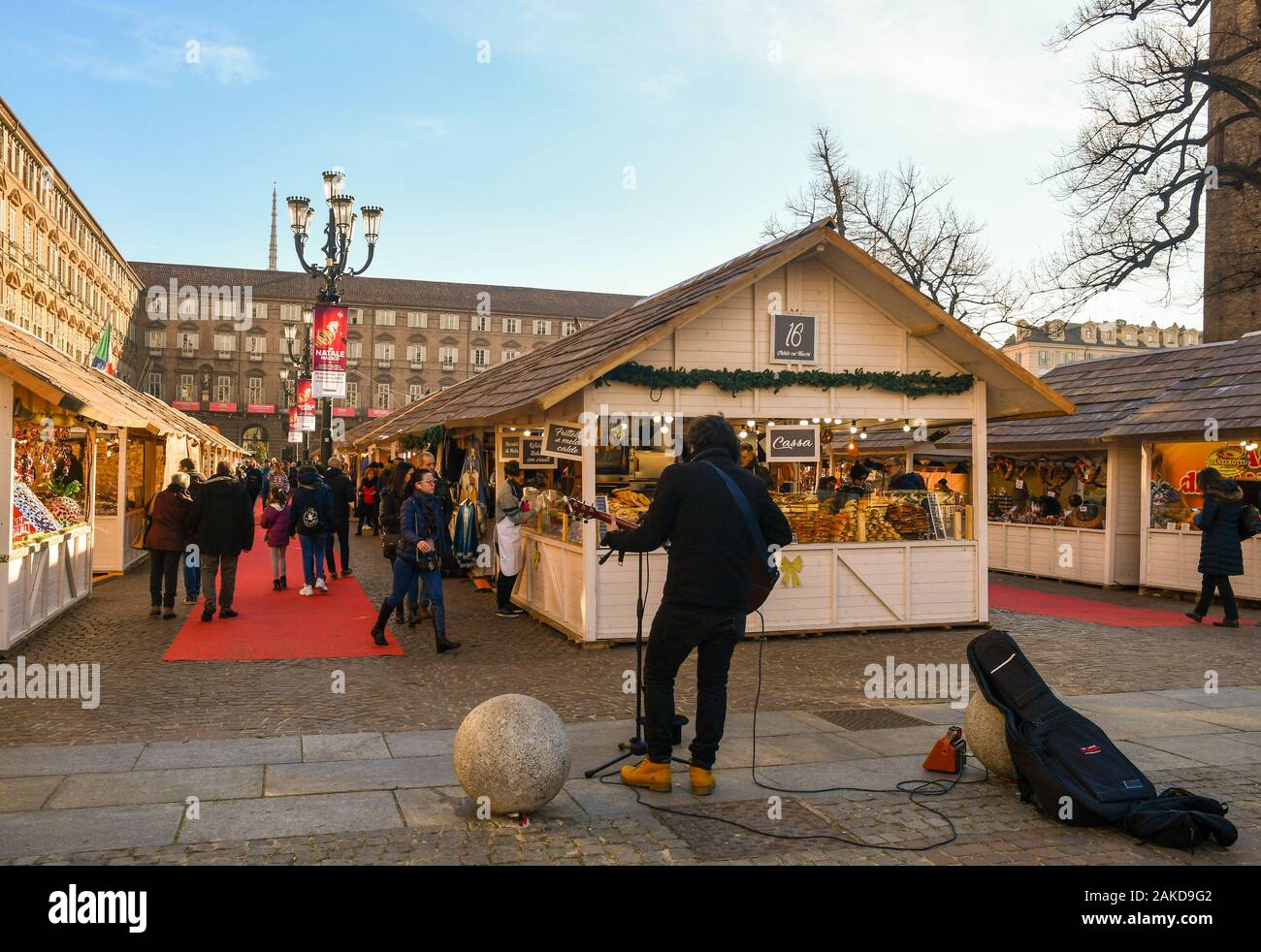The Christmas market in Piazza Castello square in the centre of Turin with a street musician and people shopping on Christmas Eve, Piedmont, Turin Stock Photo
