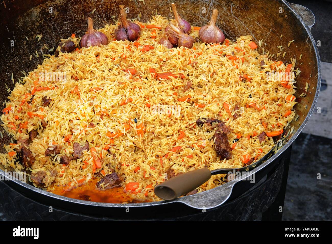 Big cauldron of asian traditional pilaf. Pilaf is cooking from rice with beef or lamb, carrot and spice. Plov close up. National food of Central Asia. Stock Photo