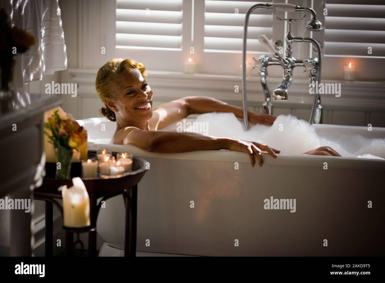 Mid-adult woman relaxing in a bubble bath surrounded by candles Stock Photo  - Alamy