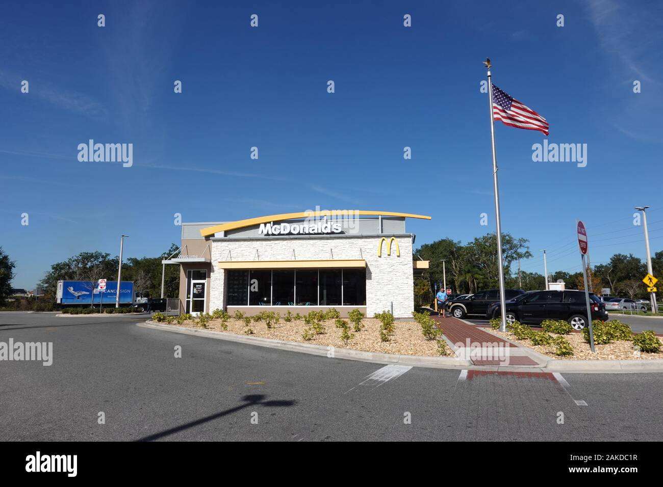 Orlando, FL/USA=1/7/20:  The exterior of a  McDonalds fast food restaurant with a US flag flying on a clear bright sunny day. Stock Photo
