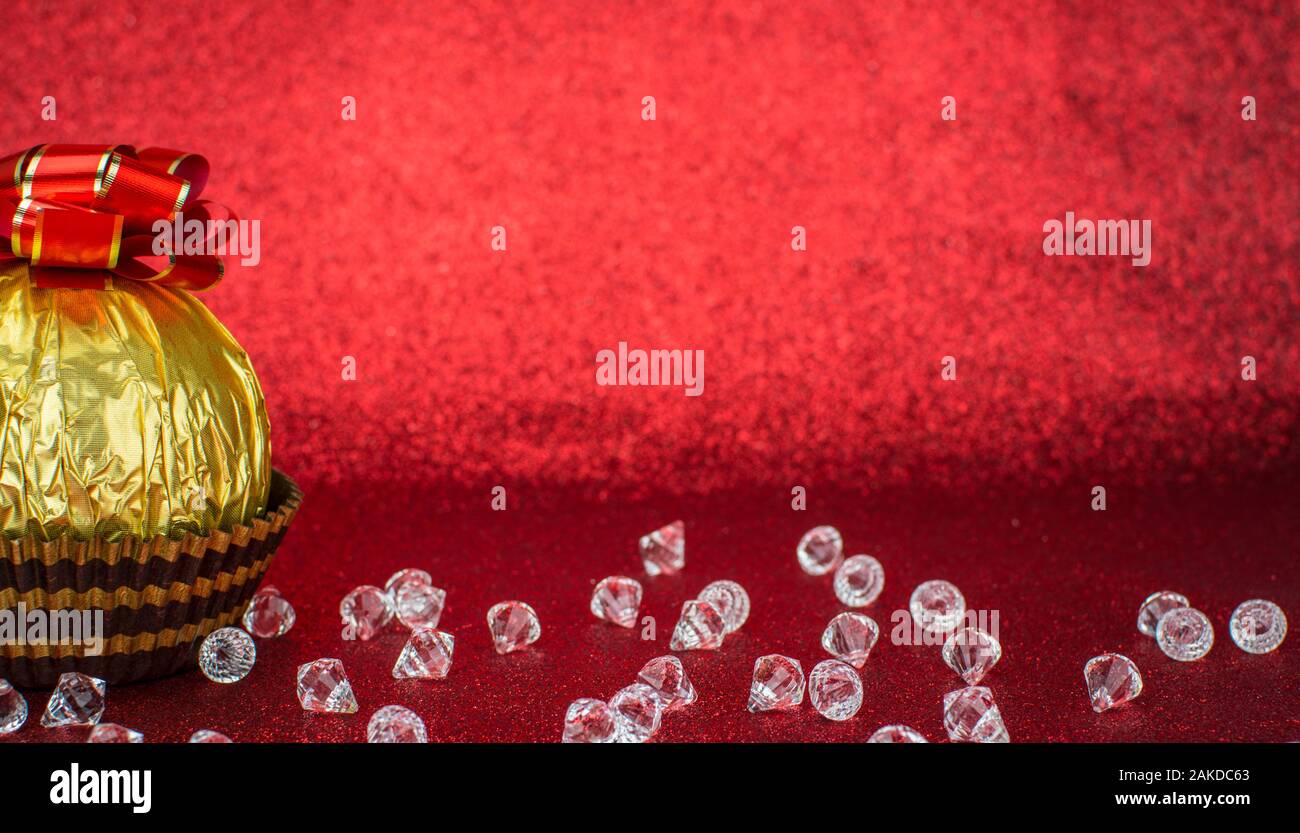 Delicious candy wrapped in gold foil on red background Stock Photo - Alamy