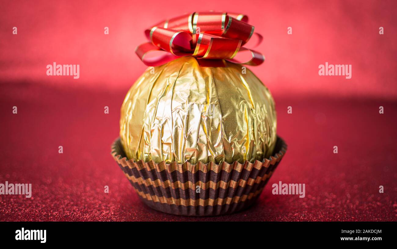 Delicious candy wrapped in gold foil on red background Stock Photo - Alamy