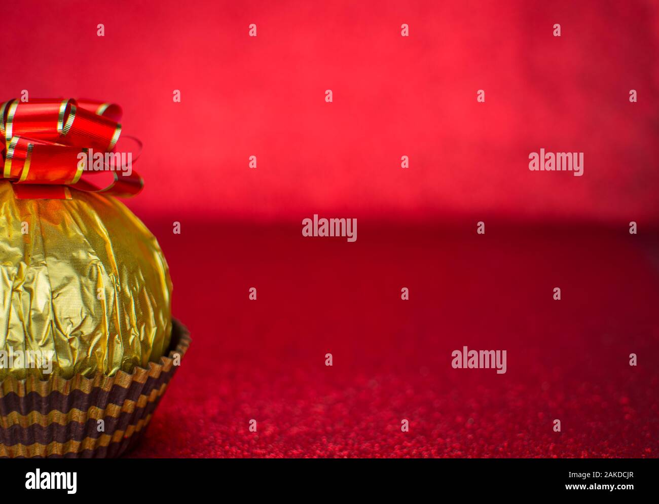 Delicious candy wrapped in gold foil on red background Stock Photo - Alamy