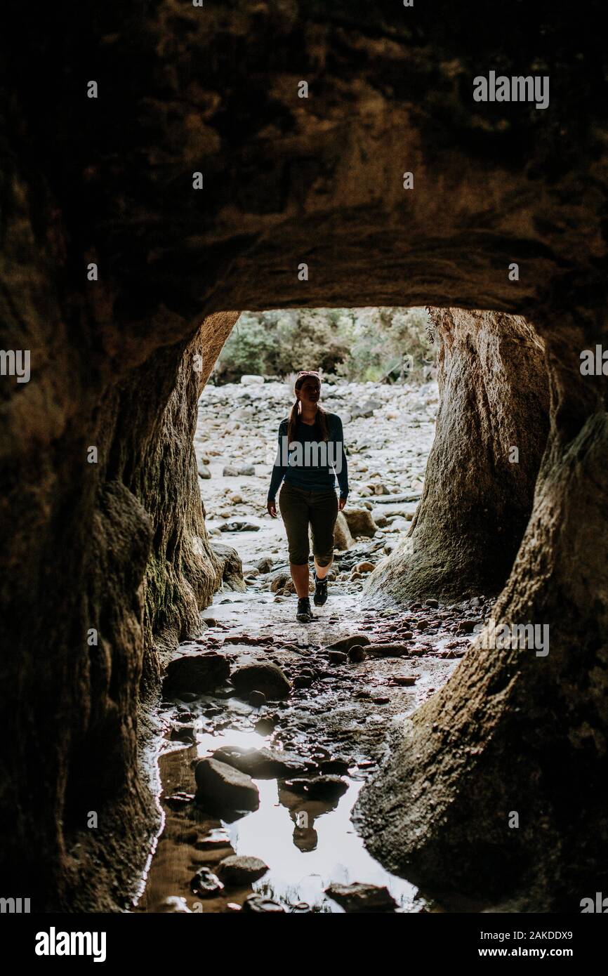Young female walks through cave in Abel Tasman Park, New Zealand Stock Photo