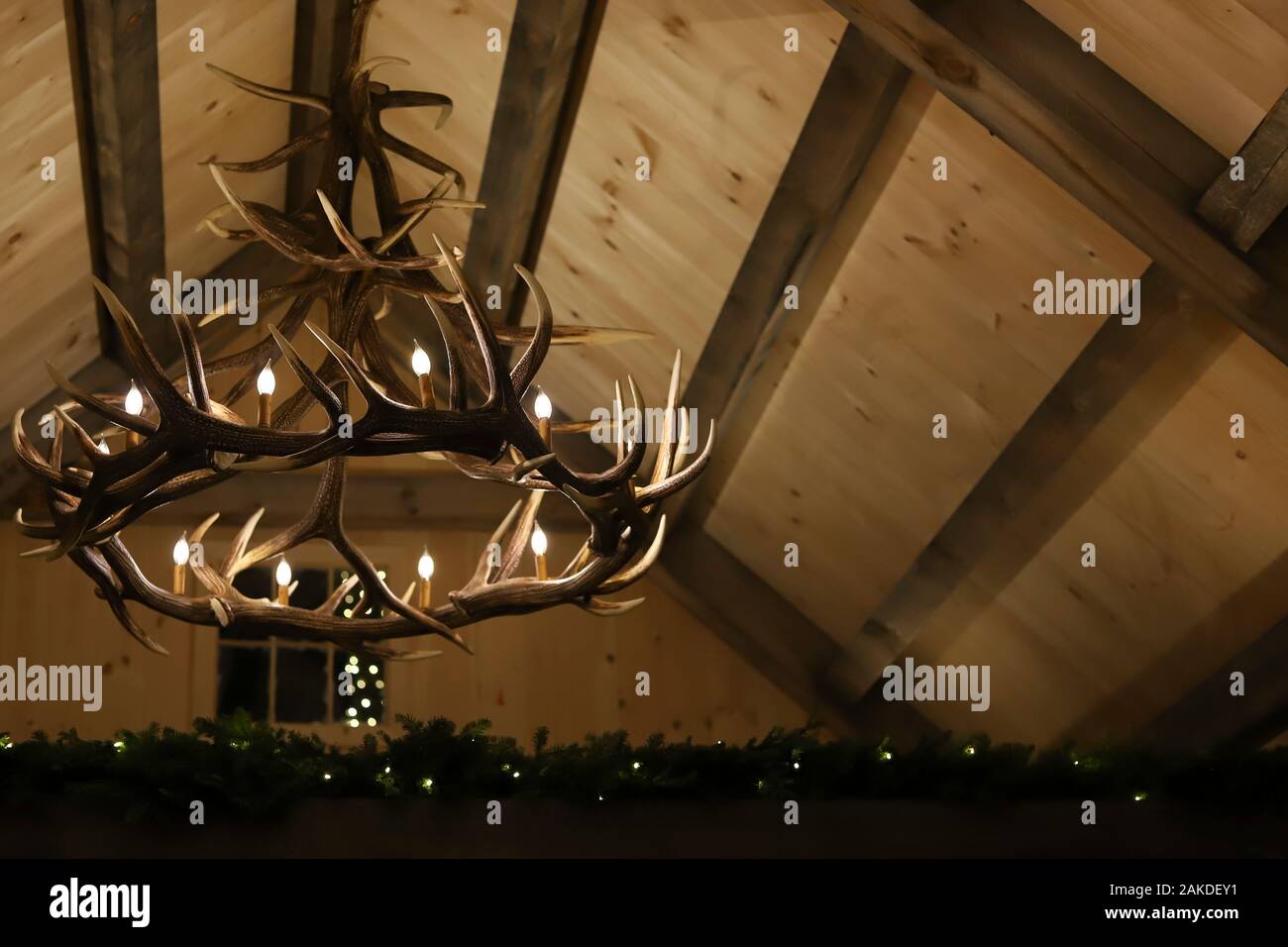 Antler chandelier and a high beam ceiling with evergreen decor Stock Photo