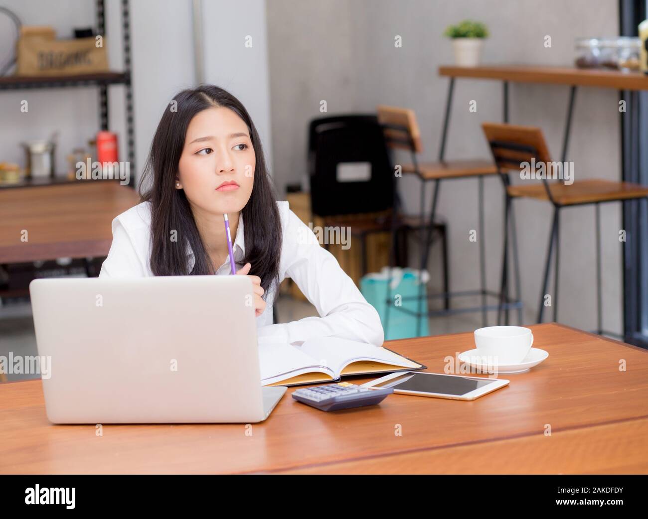 Asian young woman working online with laptop and think project for idea at ...