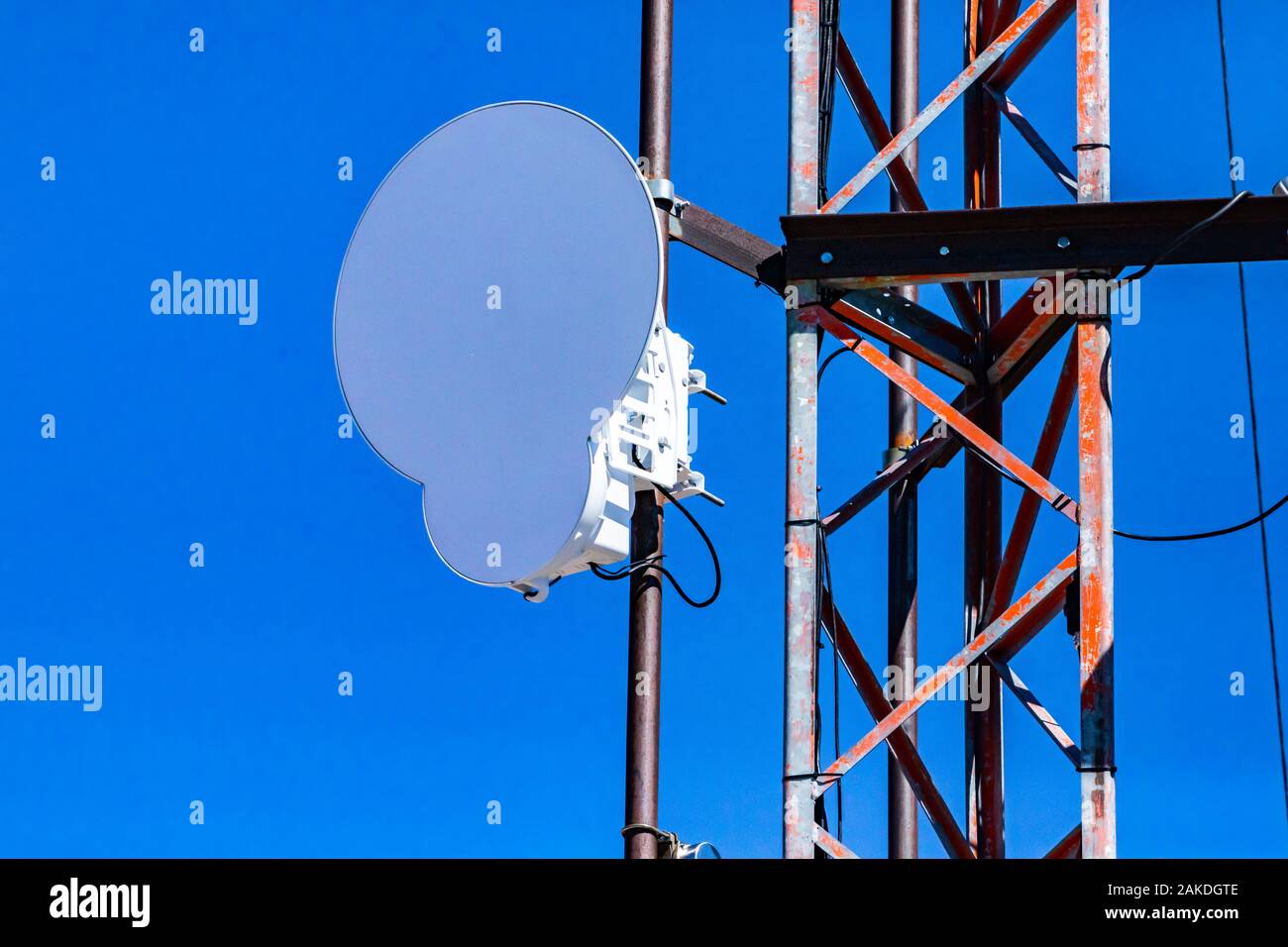 Closeup and detailed view of a circle microwave antenna fixed to steel lattice pylon. Emitting electromagnetic radiation linked to many health hazards Stock Photo