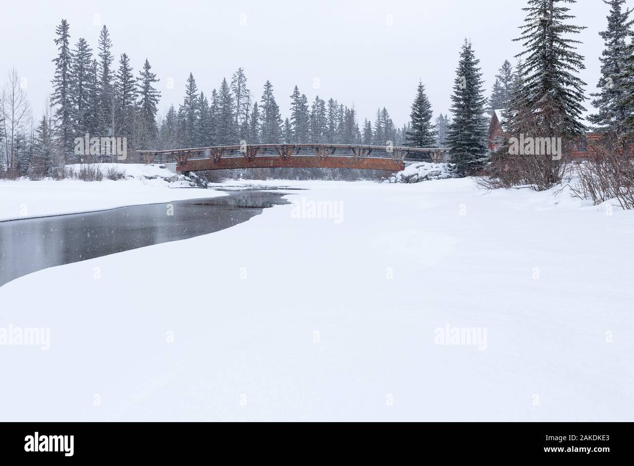 Snow falling on pedestrian bridge over Policeman's Creek in Canmore, Alberta, Canada Stock Photo