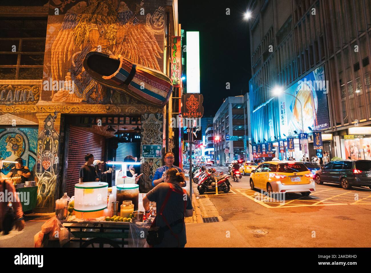 A street vendor sells refreshments on a street corner opposite a giant clog is mounted on the wall of Macanna shoe store Stock Photo