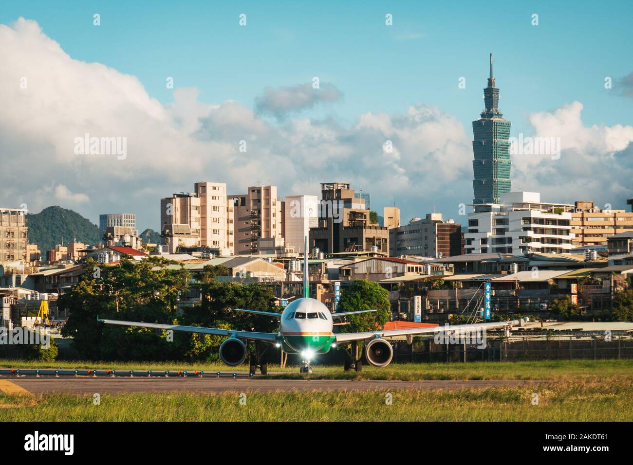 An EVA Air Airbus A321 lines up for takeoff on a sunny evening at Taipei's Songshan Airport. The Taipei 101 skyscraper is visible behind Stock Photo