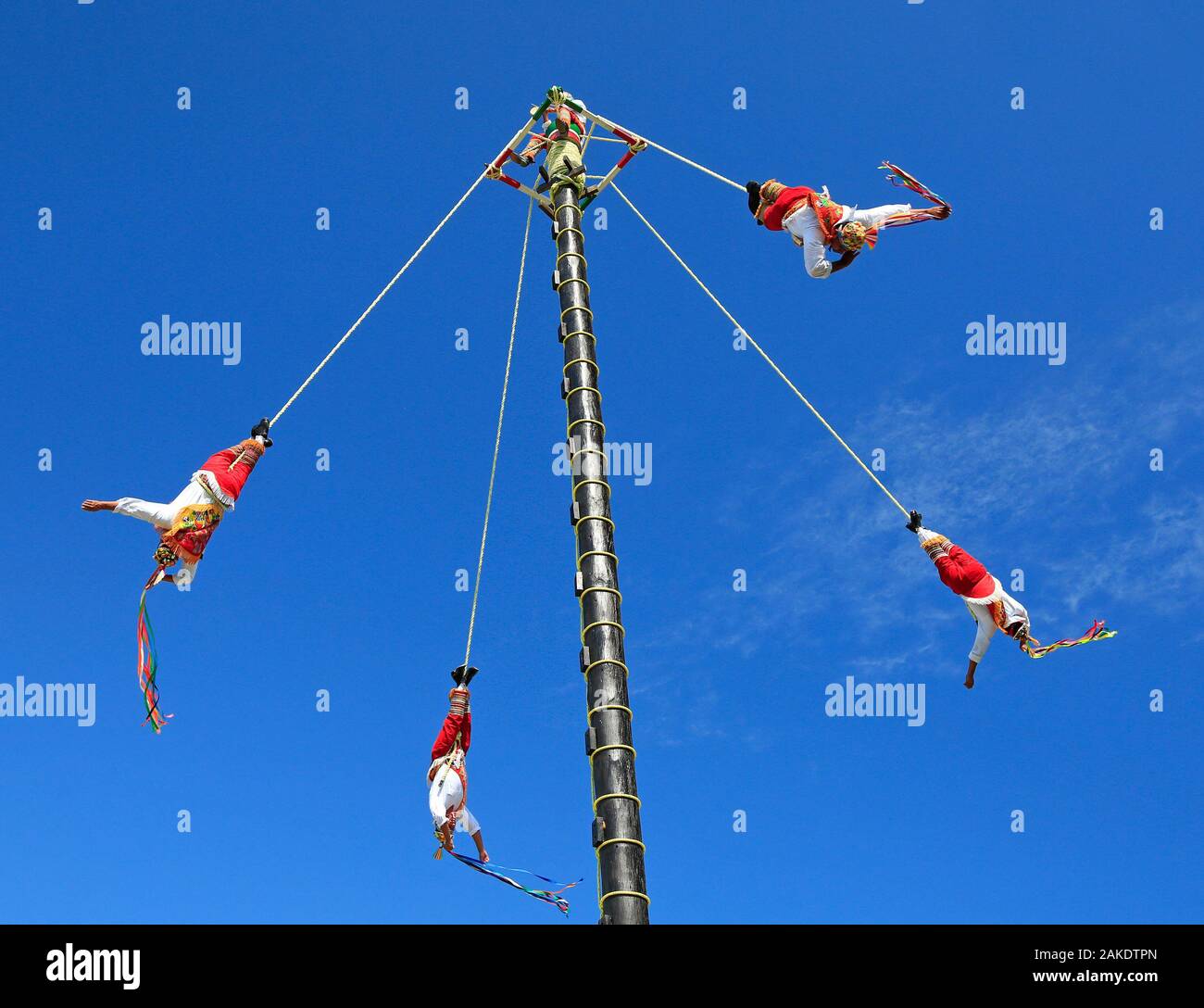 The Voladores, or flyers performance. They climb up a very high pole their waist to ropes wound around the pole and then jump off, flying gracefully a Stock Photo