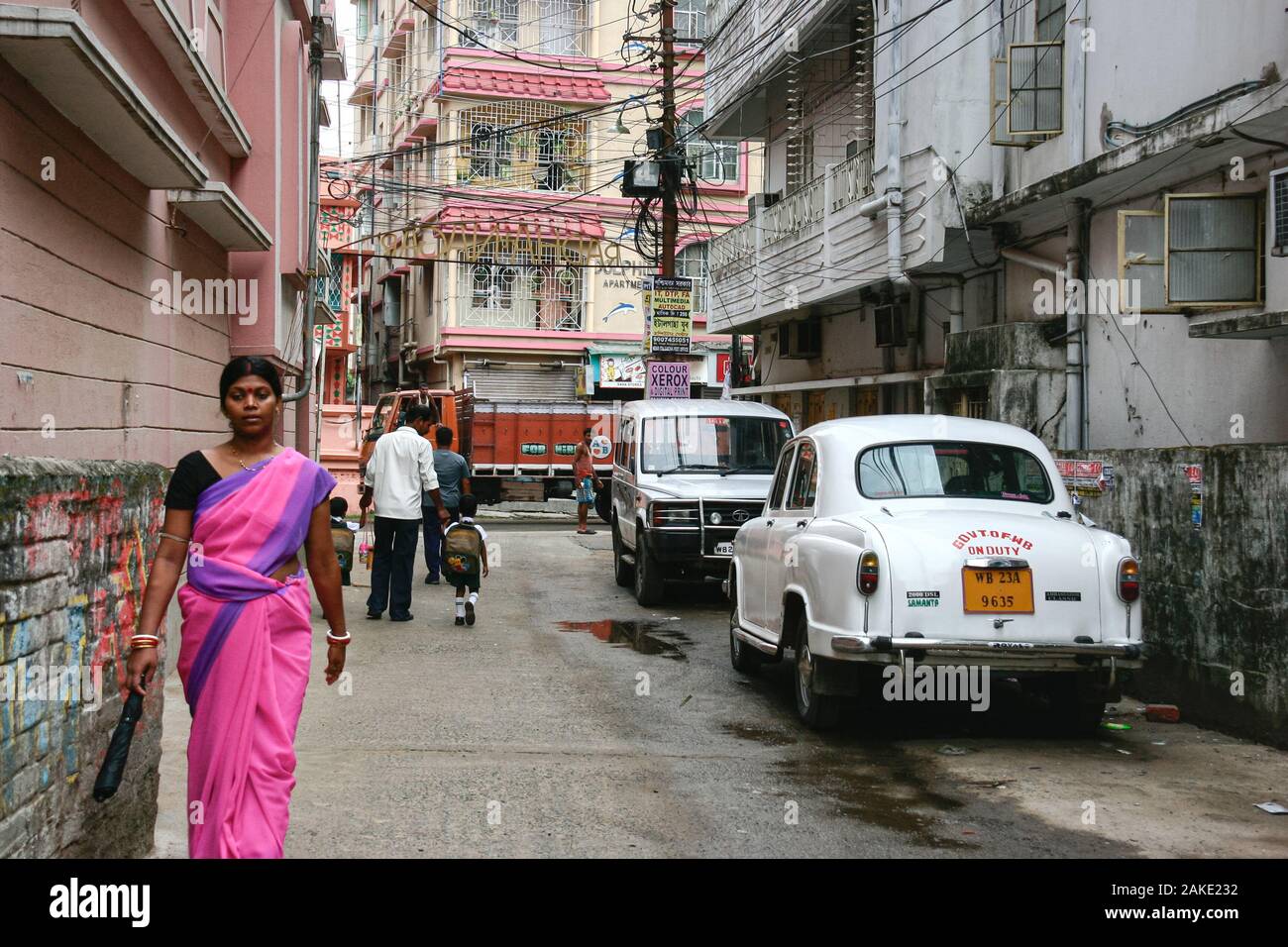 Kolkata, India - December 5, 2019 : indian woman in sari or saree traditional dress walking to work with father holding child hand to go to school on Stock Photo