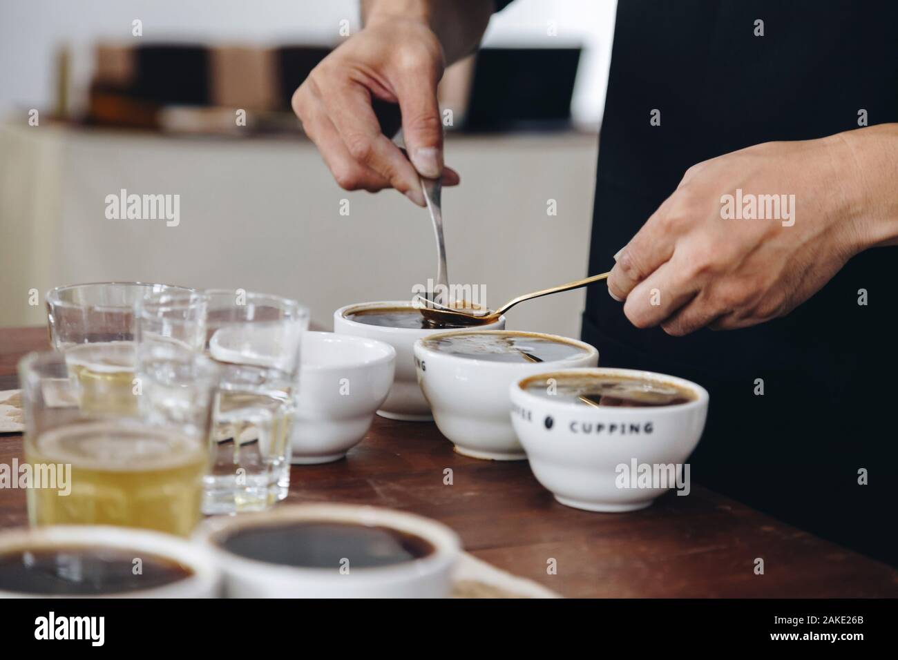 professional Q Grader preparing to test and inspecting the quality of coffee and skim off the coffee grounds from ceramic cup on the table. film style Stock Photo