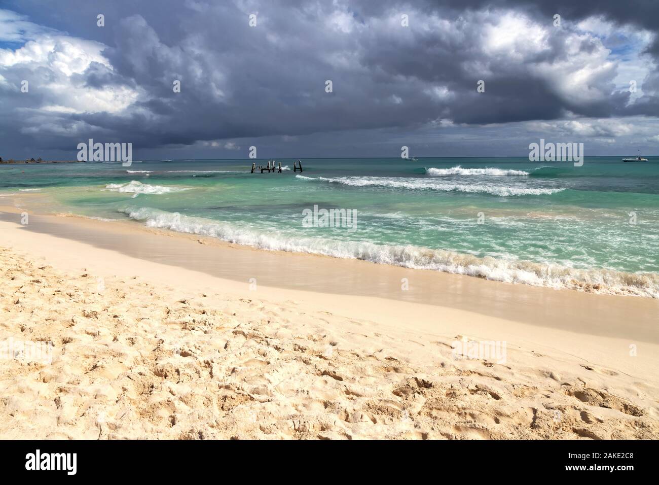 Dark clouds form over the sea with waves crashing the beach as storm approaches. Stock Photo