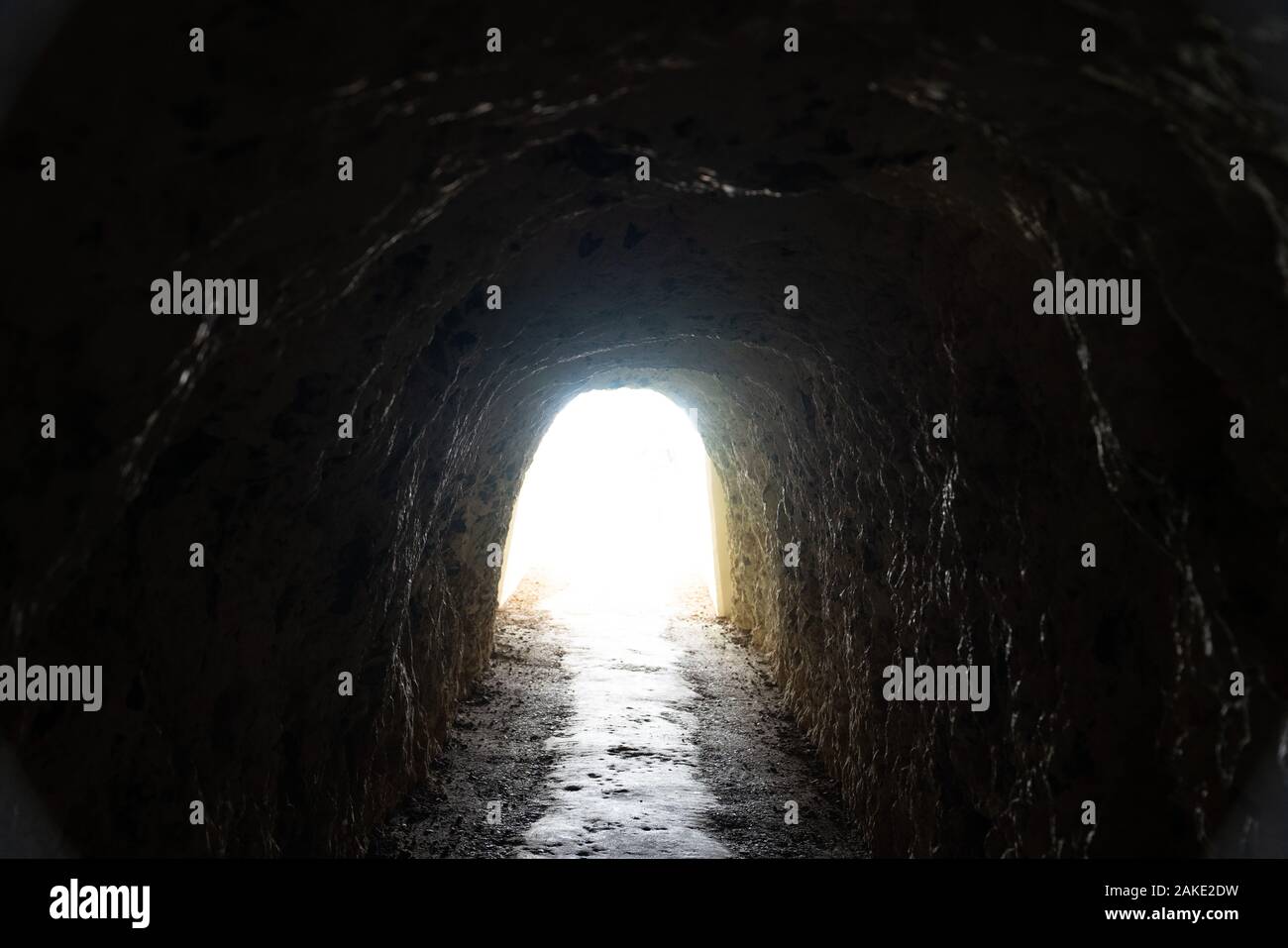 Tunnel exit with flight flowing in from dark rocky cavern Stock Photo