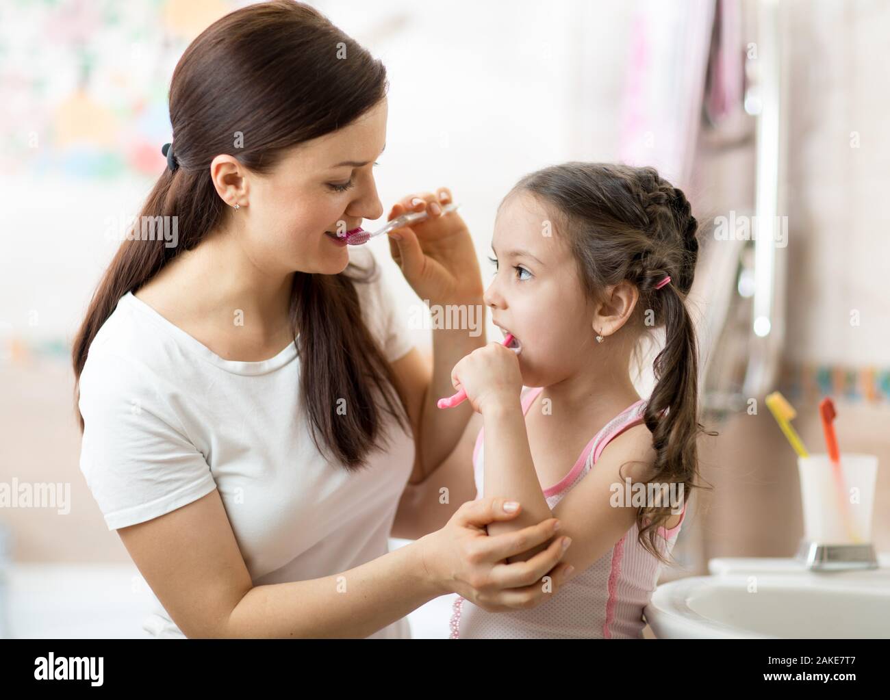 Mother teaches her child daughter accurately brushing teeth Stock Photo