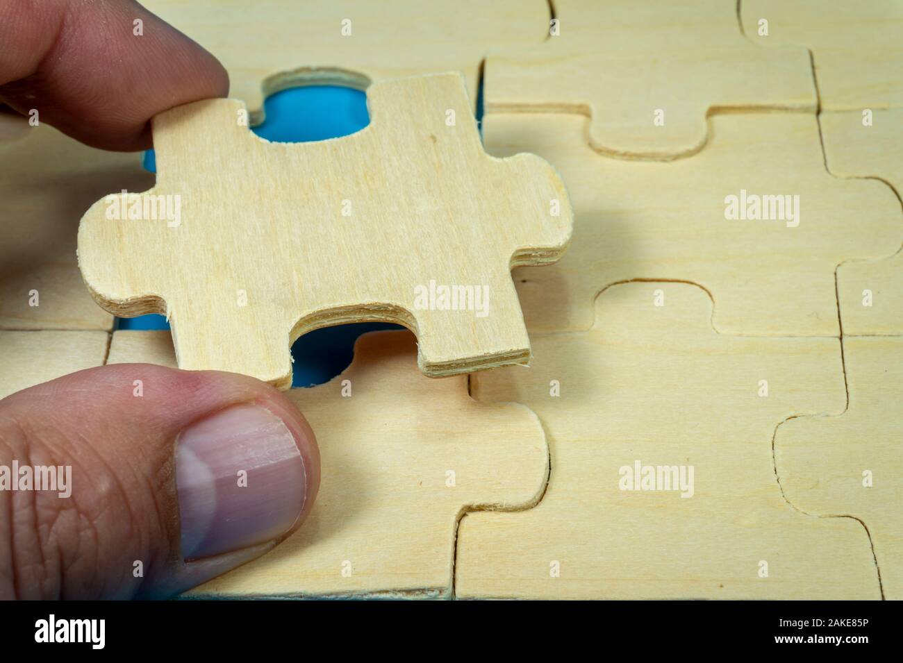 Unpainted plywood puzzles with hand holding one piece taken out