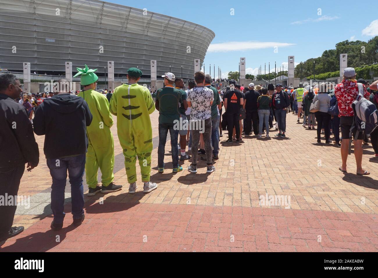 Rugby sevens tournament or sports event at Cape Town stadium in Green Point where people queue to get in for final day match, some wear fancy dress Stock Photo
