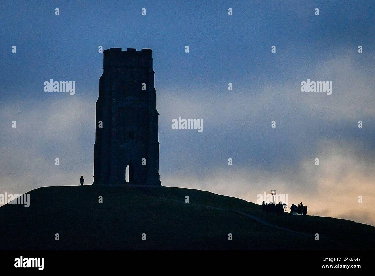 People gather at dawn by St. Michael's Tower at the top of Glastonbury Tor, Somerset, to celebrate 125 years of the National Trust, which was founded in 1895 to care for historic properties, areas of beautiful countryside and to provide access to green spaces. Stock Photo