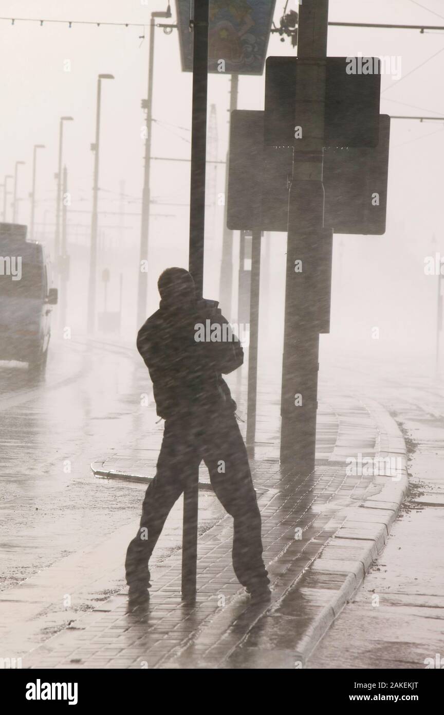 Man holding onto post during severe storm with hurricane force winds, Blackpool, England, UK, November 2007. Stock Photo