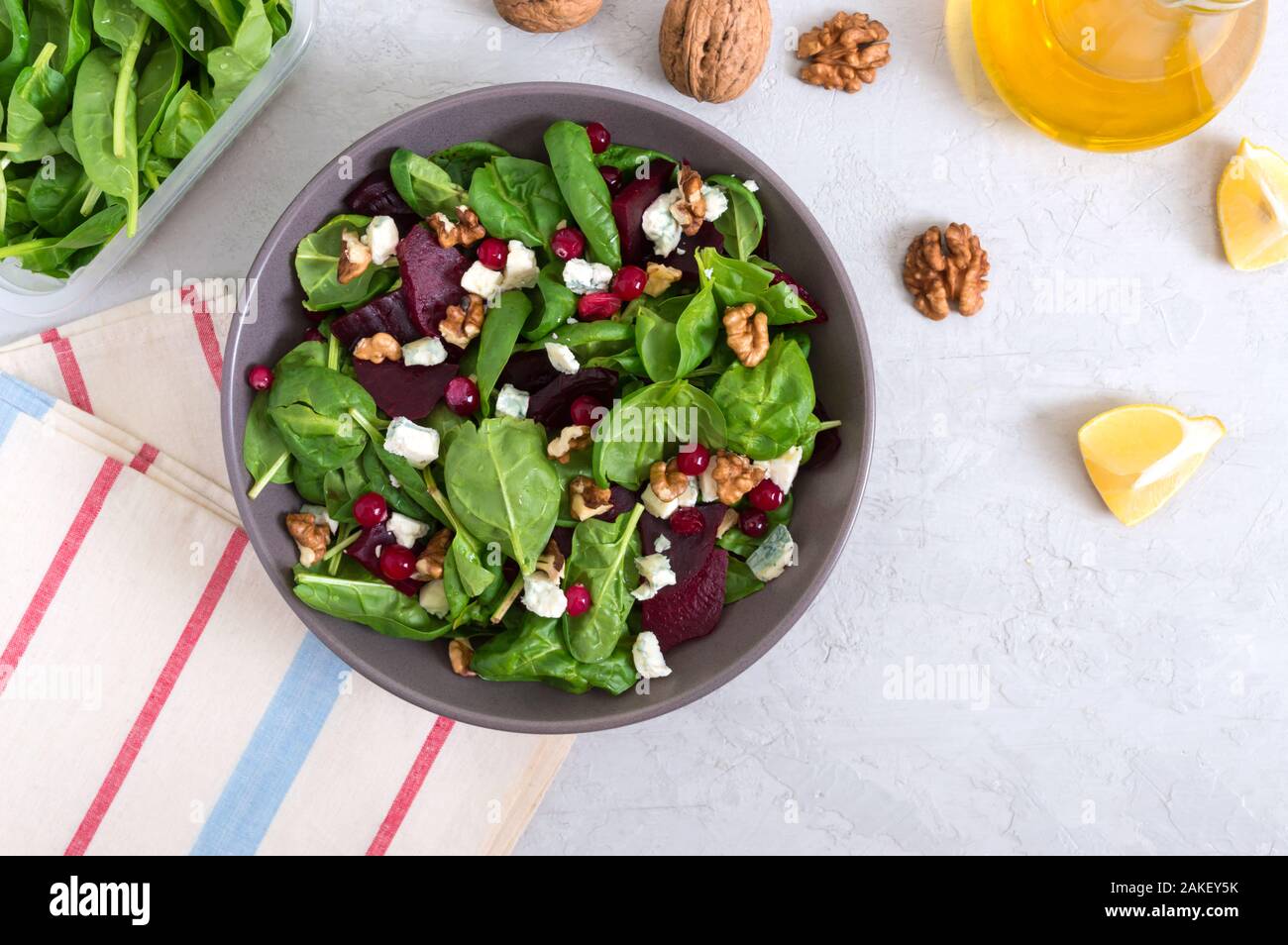 Salad with young spinach, boiled beets, blue cheese, nuts, cranberries in a bowl on a light background. Tasty diet fitness dish. Vitamin salad. Proper Stock Photo